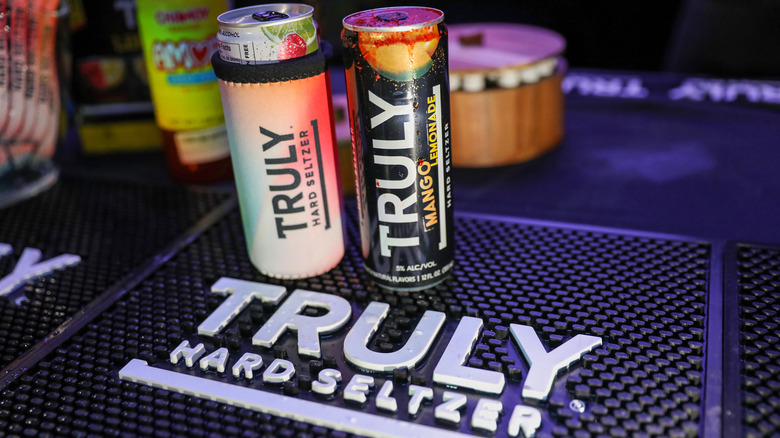 Two Truly hard seltzer cans on a branded bar mat