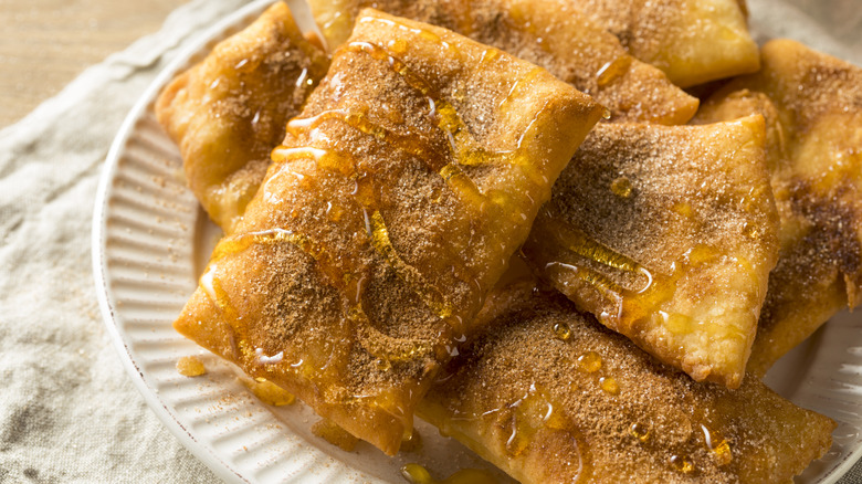 White plate of cinnamon sugar sopapillas with honey drizzle