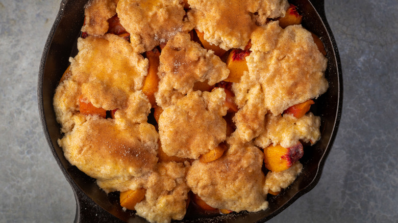 top view of peach cobbler in cast iron skillet on grey counter