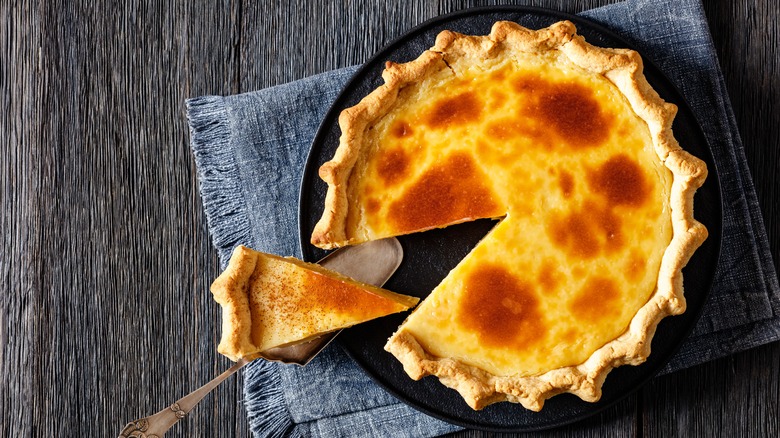 Overhead shot of Hoosier sugar cream pie with slice removed on wooden table and a gray cloth