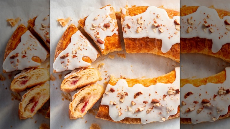 Sliced kringle pastry on marble counter covered in a white glaze and crushed almonds