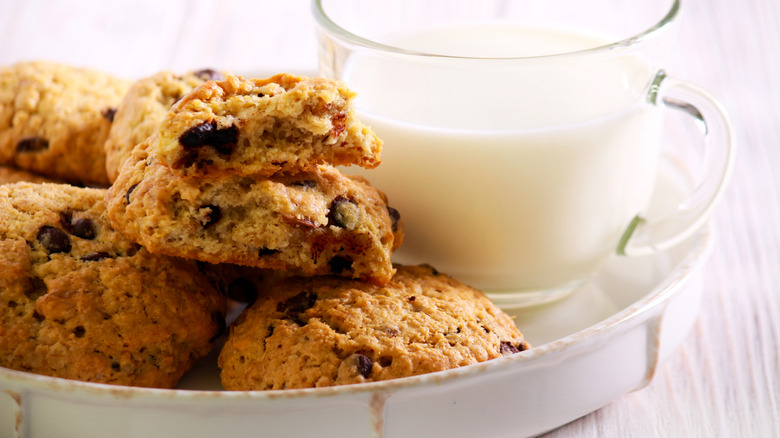 White plate stacked with cowboy cookies next to a glass of milk