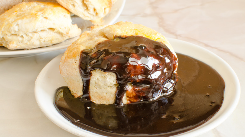 Biscuit on white plate in pool of chocolate gravy