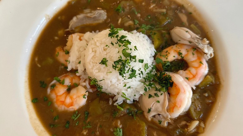 Close-up of seafood gumbo in white bowl with scoop of rice