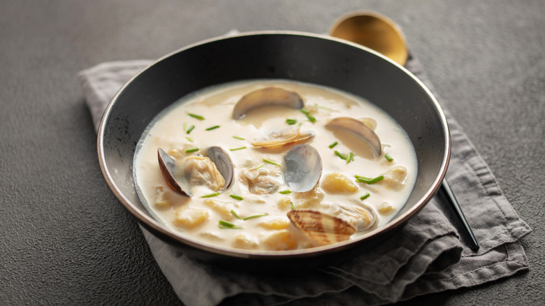 Bowl of clam chowder on napkin on grey background