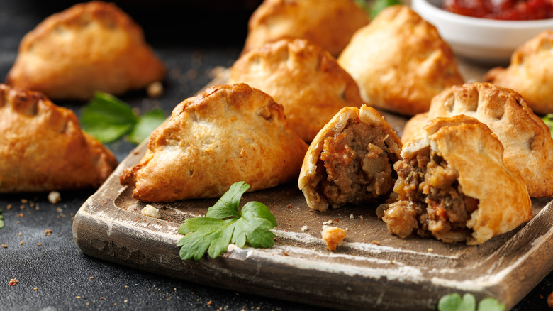 Platter of pasties with one open and meat spilling out