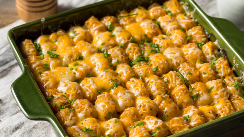 Casserole in green dish topped with tater tots and cheese