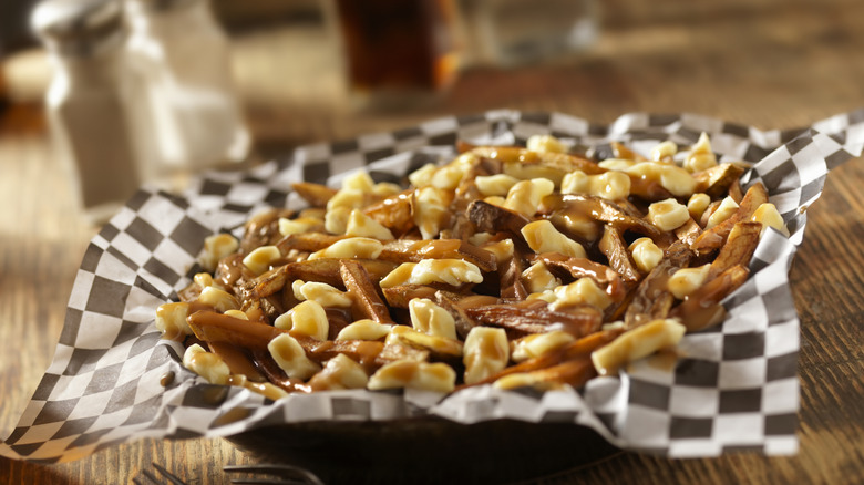 Poutine in basket with checkered paper on restaurant table