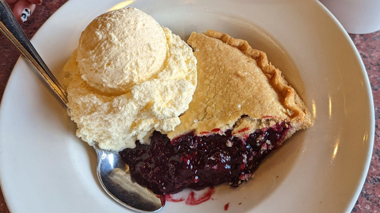 Marionberry pie with a scoop of ice cream in white dish at diner