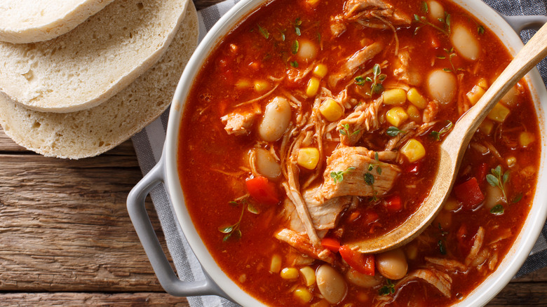 Spoon scooping Brunswick stew in white dutch oven with side of bread