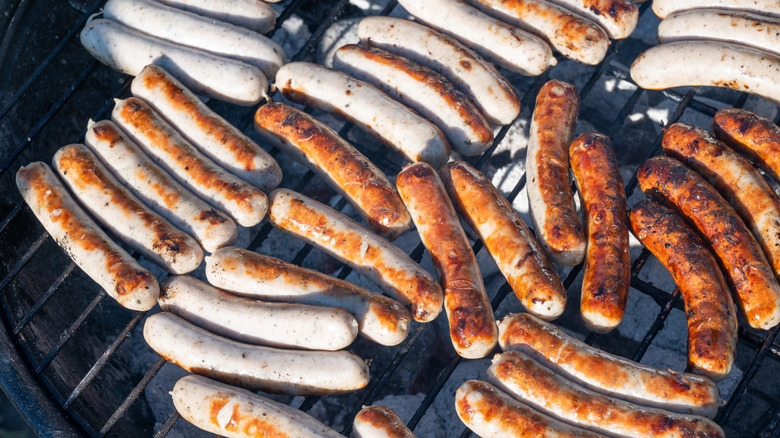 Dozens of bratwursts cooking on a grill