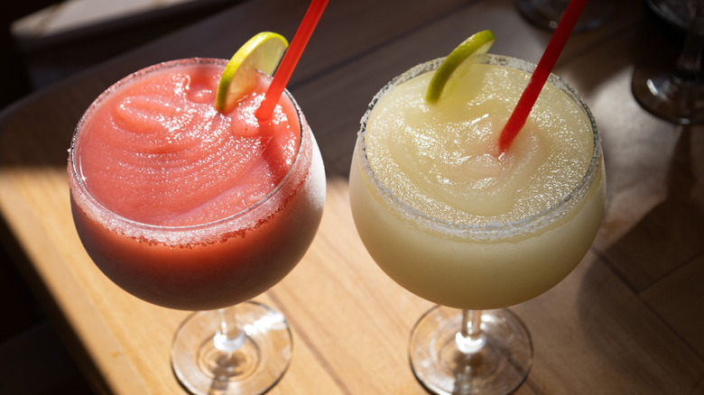 Red and yellow blended daiquiris with lime wedge and straw