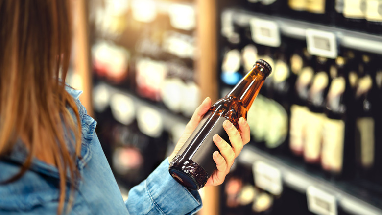 person looking at beer bottle in store