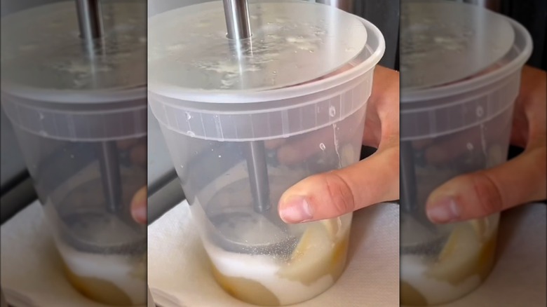 Hand holding a plastic container while muddling lemons and sugar 