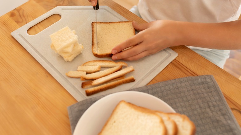 Cutting crust off sliced of bread