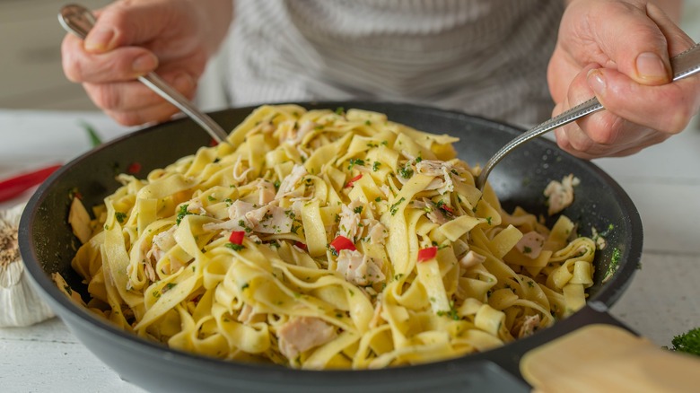 tossing pasta in a skillet