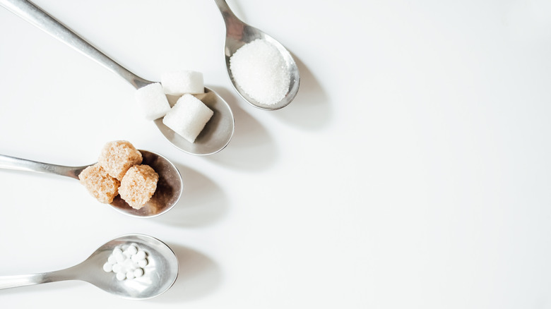 Four sugar substitutes in metal spoons 