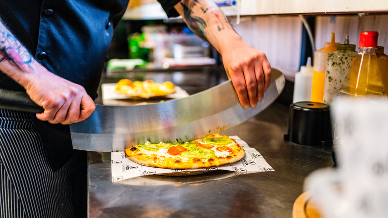 Chef cutting pizza with knife