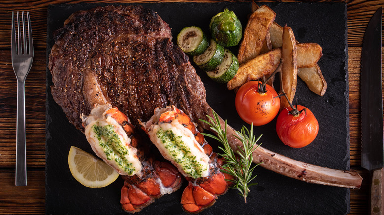 Tomahawk steak with lobster tails and grilled vegetables