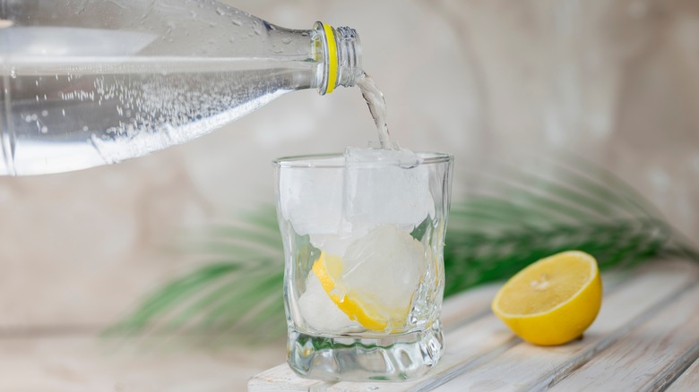 pouring tonic into glass with ice