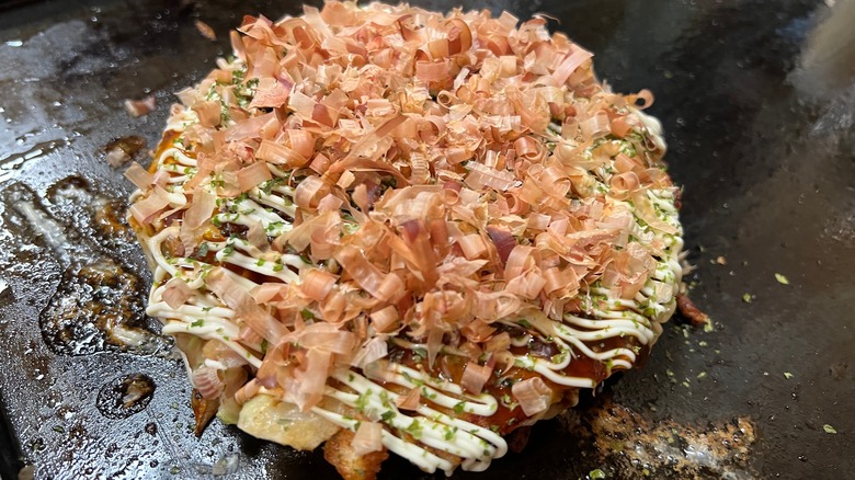 Bonito-topped okonomiyaki on griddle