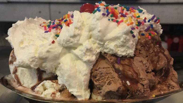A huge ice cream sundae with whipped cream and sprinkles.