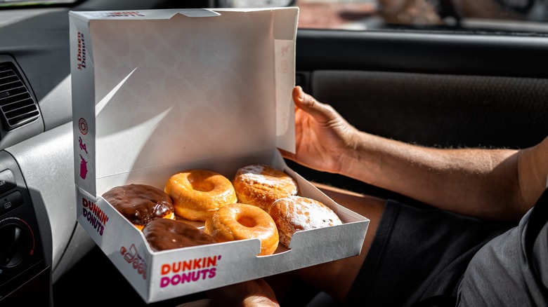 Person opening a box of Dunkin' donuts