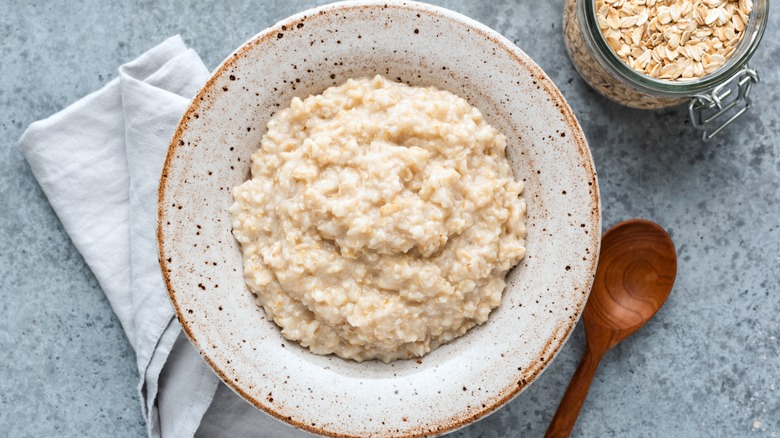 cooked oatmeal in bowl with spoon on side