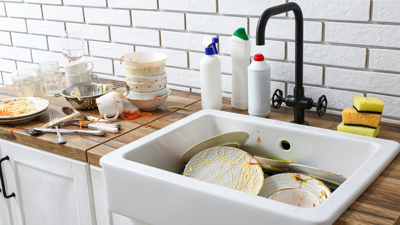 Wooden counter with ceramic sink and dirty dishes in kitchen