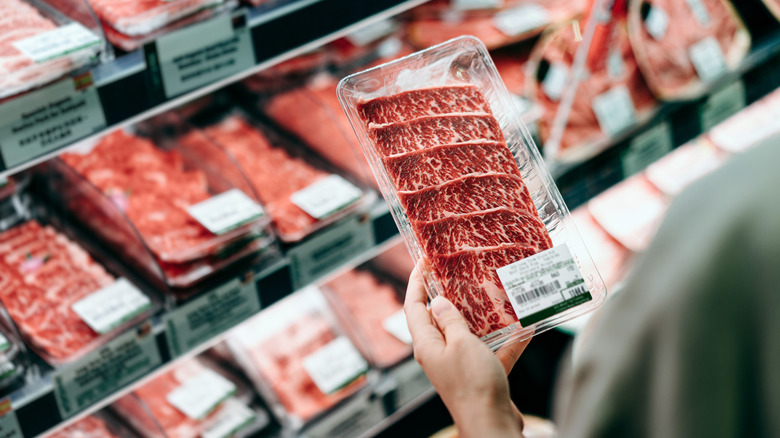 person shopping for steak at the grocery store