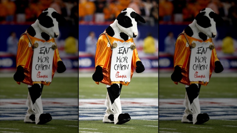 A mascot wears a sign with Chick-fil-A's slogan "Eat Mor Chikin" written on it