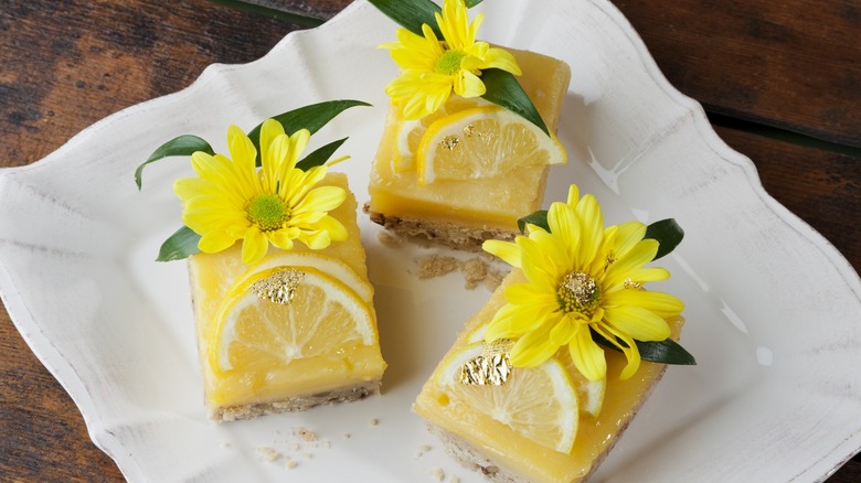 Top-down view of three lemon bars garnished with yellow flowers