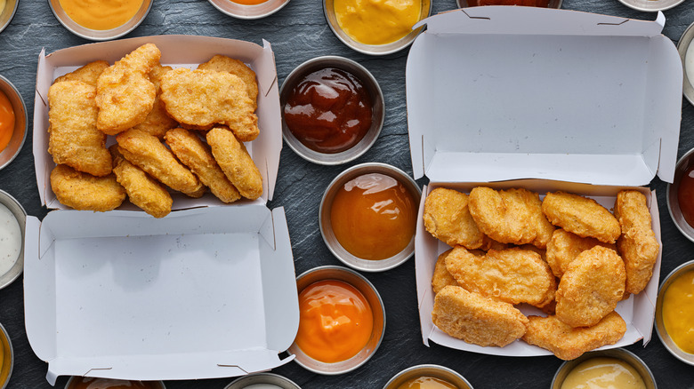 Fast food chicken nuggets surrounded by sauce cups