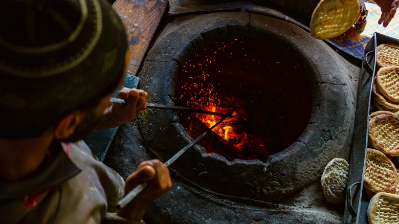 stoking fire in tandoor oven