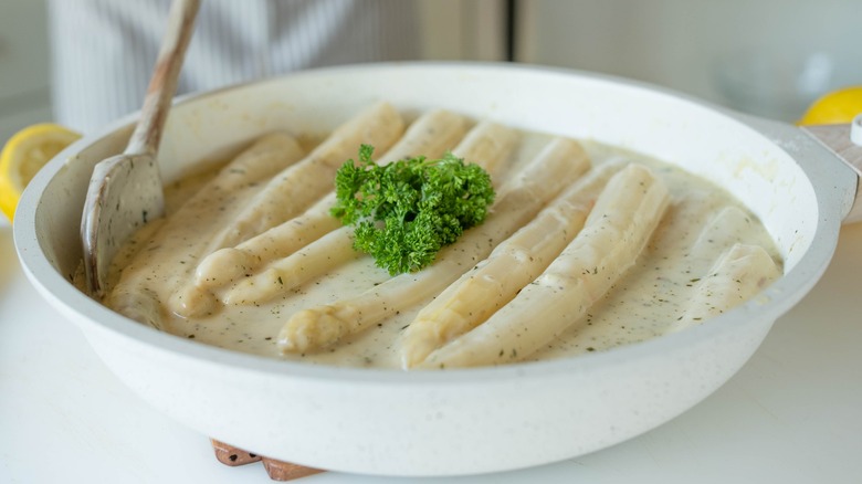 white asparagus in a bowl of bechamel sauce