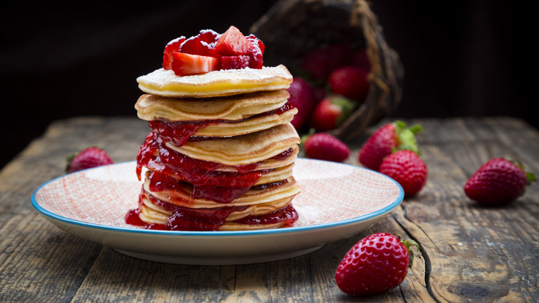 Stack of pancakes with strawberry jam oozing out between the layers