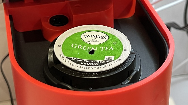 A used Twinings Green Tea K-cup in the pod holder of a red Keurig