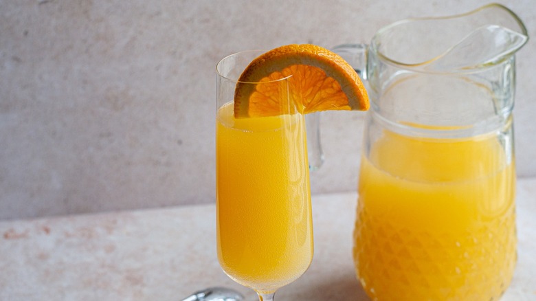 A Mimosa cocktail next to a full pitcher