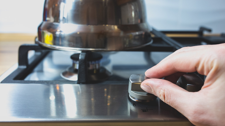 Hand turning knob on gas stove