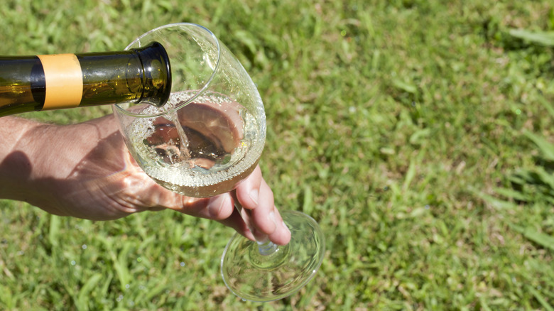 Hand pours white wine into glass