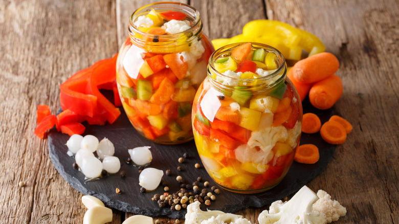 jars of giardiniera on stone plate surrounded by ingredients