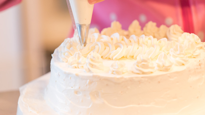 piping frosting on the top of a cake