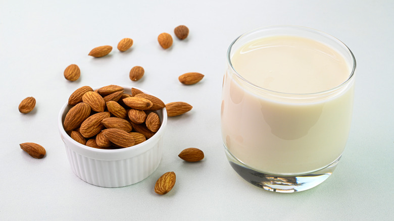 glass of almond milk next to bowl of almonds