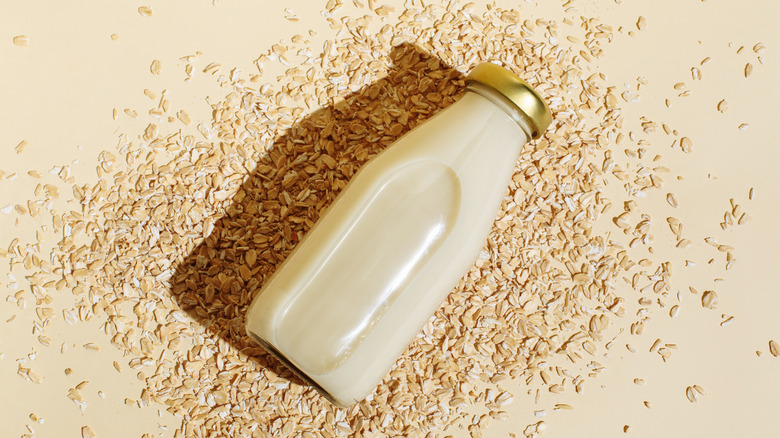 glass bottle of oat milk atop oats