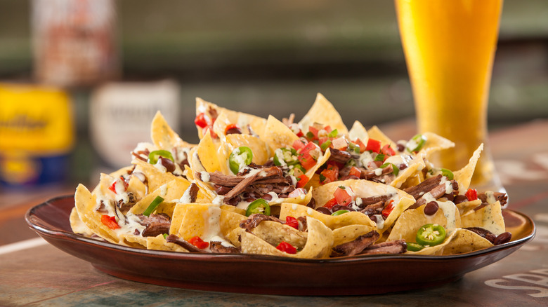 A plate of nachos with a beer