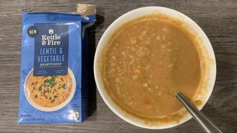 front of the Kettle & Fire lentil and vegetable packaging with a bowl of the soup