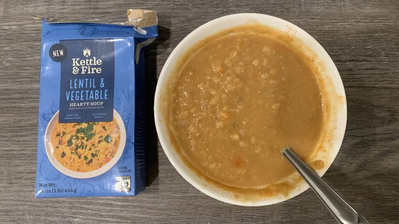 A bowl of Kettle & Fire lentil and vegetable soup next to the box it came out of