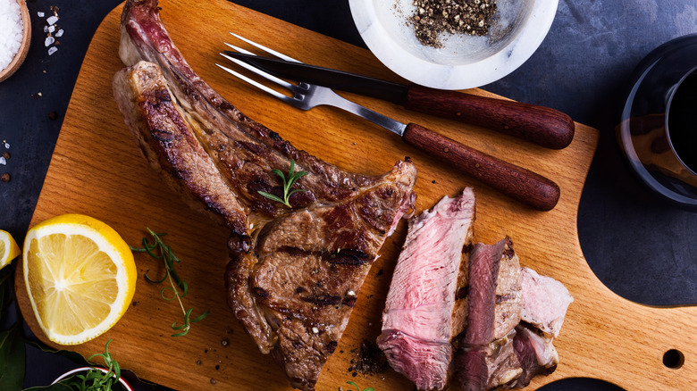 prime rib roast on cutting board with lemon and utensils