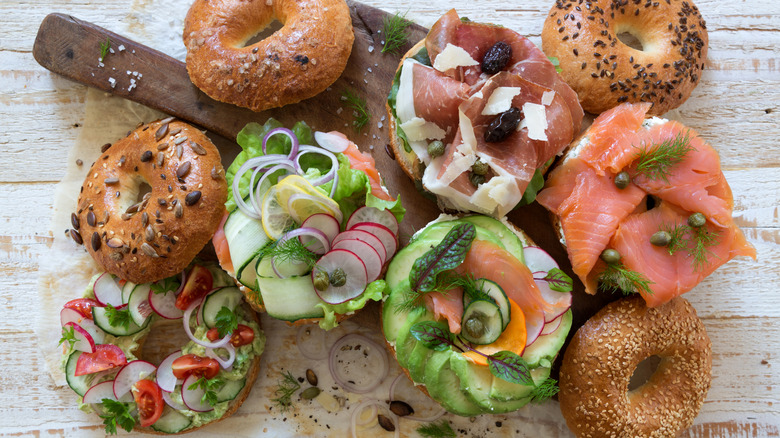 spread of bagels with different toppings on wooden surfaces