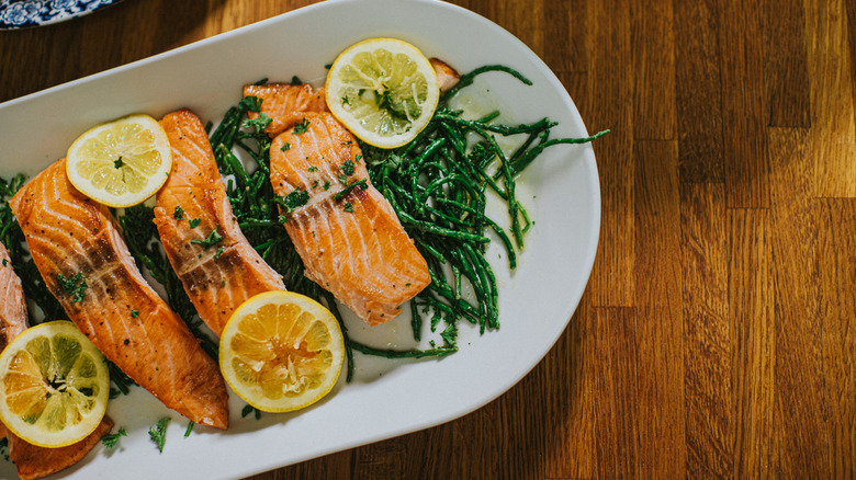 A plate of grilled salmon filets with greens and lemon slices